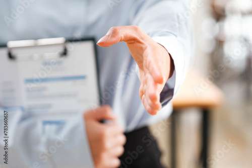 Businessperson's hand outstretched for a handshake, signaling readiness to engage.