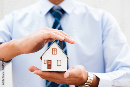 Hands holding a small house model, depicting safety and security in homeownership.
