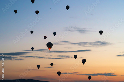 Hot air balloons rising over the landscape of the Red Valley, Rose Valley before sunrise, close to Goreme, Cavusin, Cappadocia, Turkey