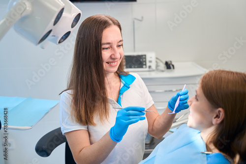Female hygienist begins to examine oral cavity of young patient