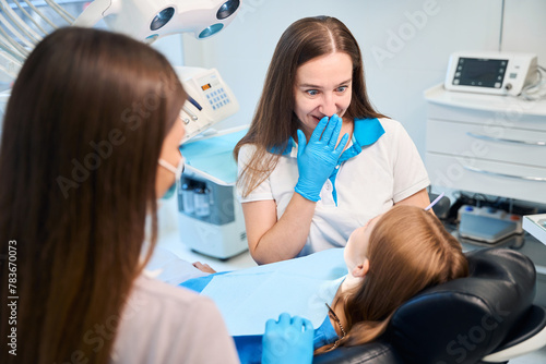 Hygienist and an assistant are conducting appointment in dental office