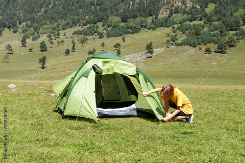 Camping skills concept. Camping and hiking. Vacation in mountains. Camping trip. Girl is setting up tent on top mountain. Temporary housing