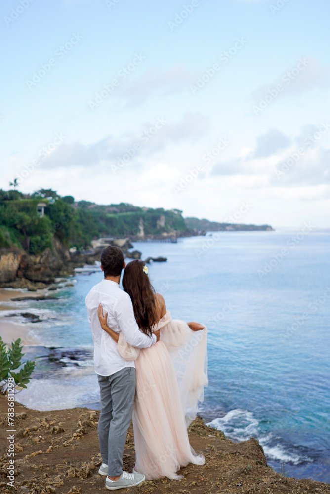 On the tropical cliff, the couple hugs with joy On the tropical cliff, the couple hugs with joy