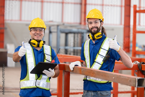 Two caucasian iron welding workers with tablet in front of the red steel structure photo