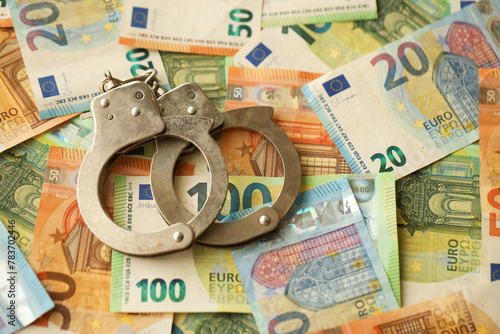 Many European euro money bills and handcuffs. Lot of banknotes of European union currency and cuffs close up photo