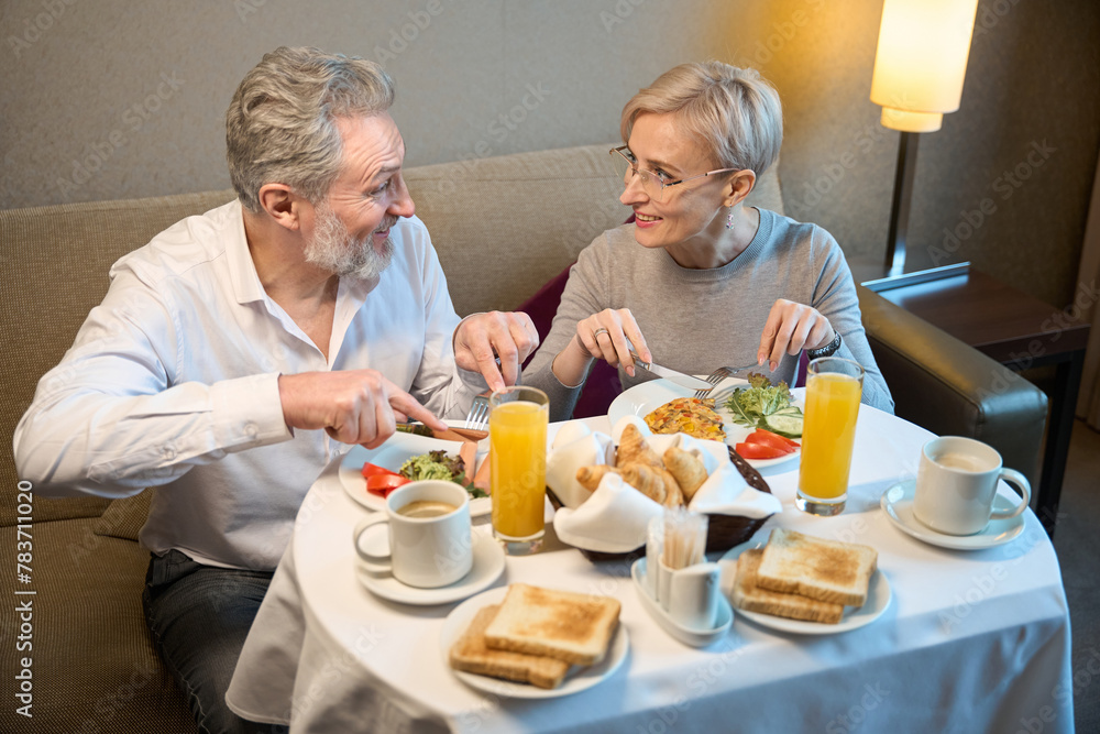 Smiling adult caucasian couple having breakfast and looking at each other Smiling adult caucasian couple having breakfast and looking at each other