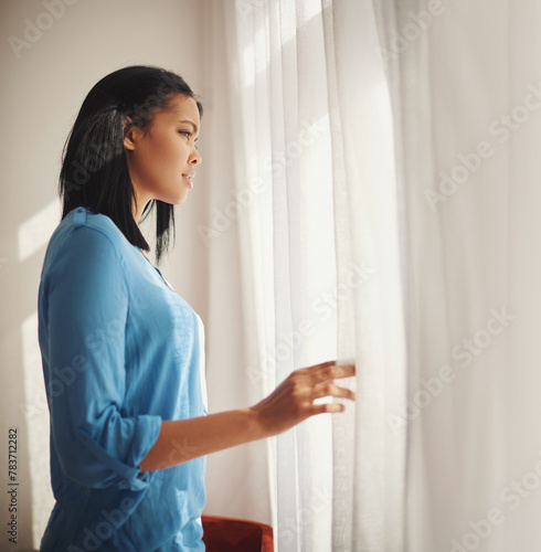 Stress, african woman, looking at living room window with anxiety, confused and worry. Curious, female person and waiting for partner, spying through curtain with concern or fear for home intruder photo