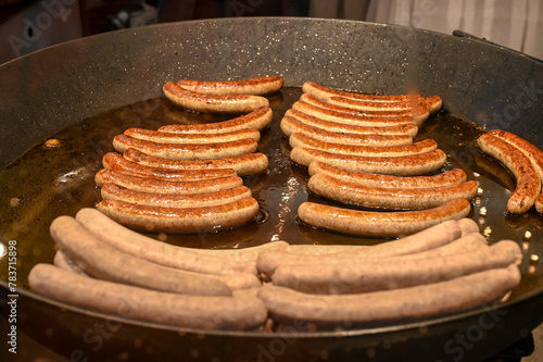 Sausages are fried in a pan, close-up. Delicious Sausage for sale on the street. Fast food. 