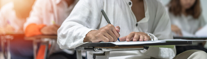 School exam student's taking educational admission test in class, thinking hard, writing answer in university classroom, education and world literacy day concept