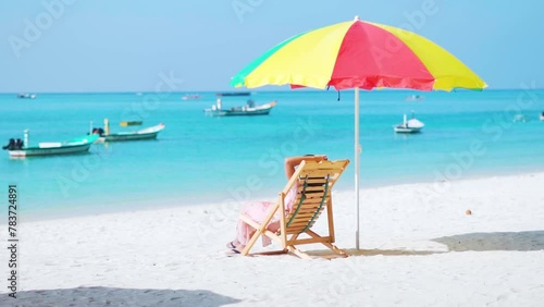 Young woman relaxing on beach chair under sun umbrella at beach in Agatti Island, Lakshadweep, India. Tourist relaxing on beach during summer vacation. Girl sitting on chair at  Beach resort. photo