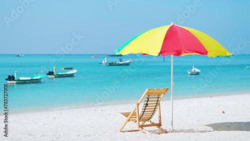 Sun umbrella and deck chairs on the beach. Boats in sea. Summer vacation background. Beach view of Agatti island, Lakshadweep, India. photo