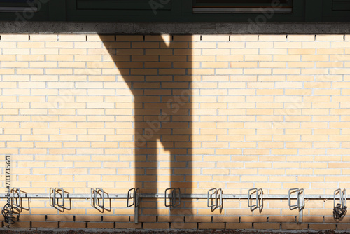 bike rack at yellow brick wall with shadows of posts in the middle