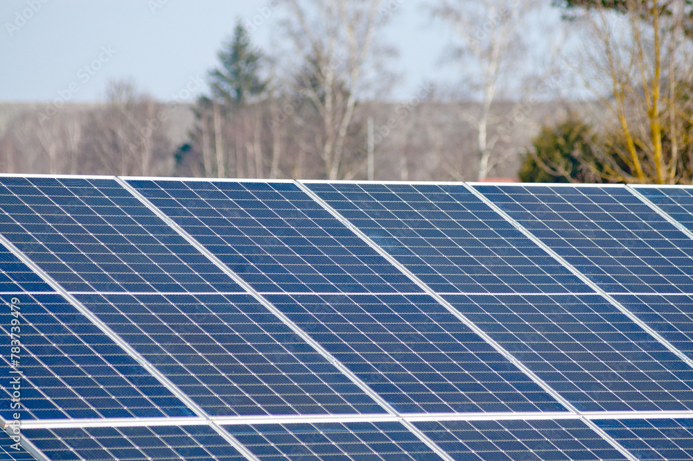 solar panels in a field against a background of green forest and blue sky solar panels in a field against a background of green forest and blue sky