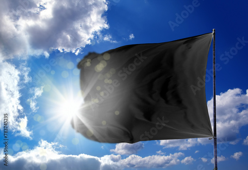 Conceptual image of waving blank black flag over sunny blue sky