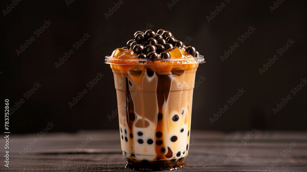 Tall plastic cup of bubble milk tea, with black pearls and brown liquid ...