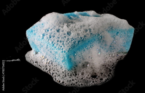 Soap foam, bubbles and blue sponge isolated on black