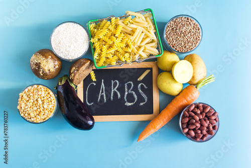 Foods containing complex carbohydrates and a sign with the inscription "carbohydrates" in close-up on a blue background