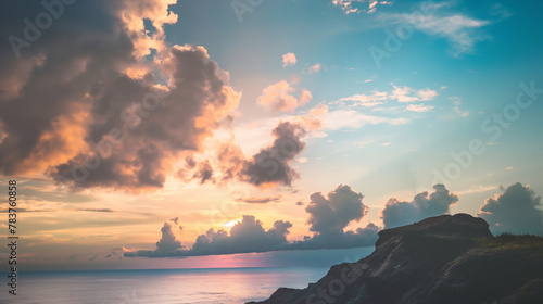 Tranquil ocean seaside rocky cliff clouds and sky during sunset