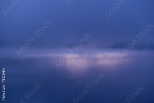 朝靄に煙る湖面を照らす朝日