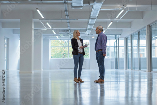 A female real estate agent shows an empty office space to a potential buyer or tenant.
