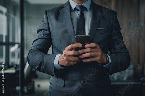 Businessman standing with smart phone in office photo