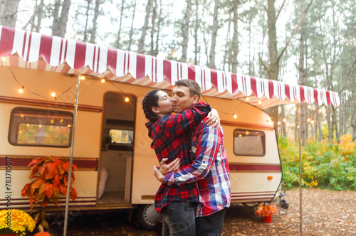 Portrait of romantic couple smiling while holding hands near house on wheels outdoors photo