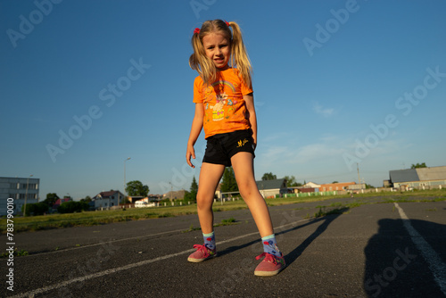 girl with long hair in an orange sweater runs in the stadium, sports, childhood, Olympics, children's sports, sports fans   © simonovstas
