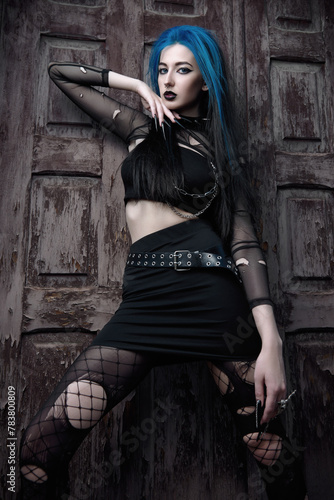 Portrait of seductive goth (deathrock) girl dressed in black skirt, holey blouse and pantyhose. Dark beauty
