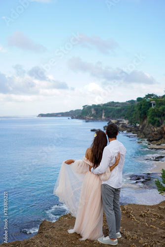 Newlyweds share a romantic embrace against the backdrop of the sea coast