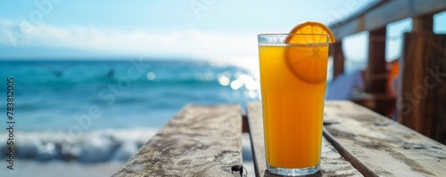 A glass of freshly squeezed orange juice stands on a wooden table in an outdoor cafe in the fresh air on the seashore on a sunny day, a summer refreshing drink for a diet and a healthy lifestyle