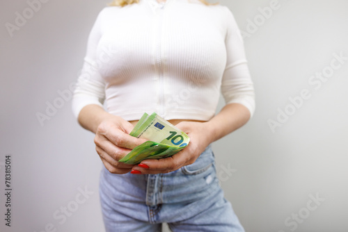 The girl holding euro bills in front of her is counting them. A girl in jeans with a euro banknote in her hands.
