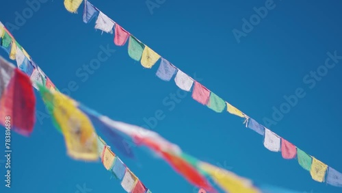 Closeup slow motion shot of Buddhist prayer flags against the clear blue sky at Sani Monastery near Padum in Zanskar Valley, Ladakh, India. Prayer flags waving in front of sky, Religious background.	