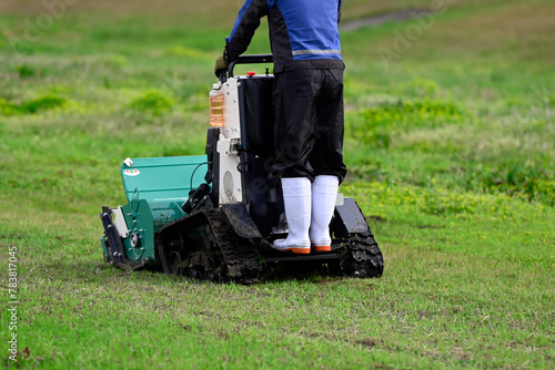 A person riding and operating a flail mower to mow the grass in the yard.