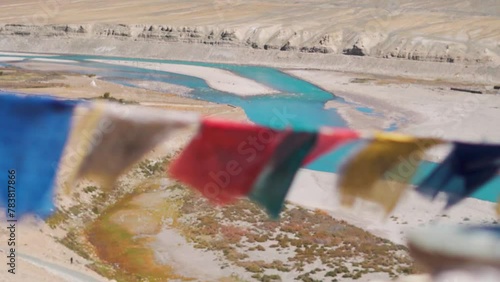 Rack focus shot of Buddhist Prayer flags waving in front of the blue coloured Zanskar river as seen from Padum village in Zanskar Valley, Ladakh, India. Focus changes from river to the Prayer Flags.