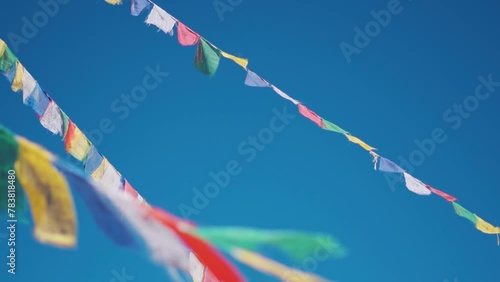 Closeup slow motion shot of Buddhist prayer flags against the clear blue sky at Sani Monastery near Padum in Zanskar Valley, Ladakh, India. Prayer flags waving in front of sky, Religious background.	