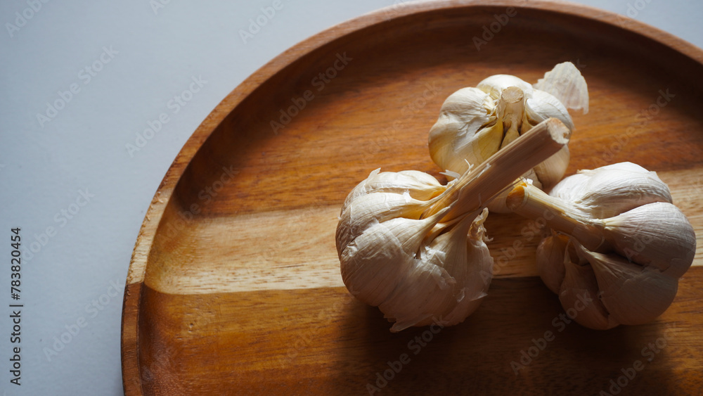 Isolated garlic or Allium sativum on a wooden tray. Selective focus                              - obrazy, fototapety, plakaty 