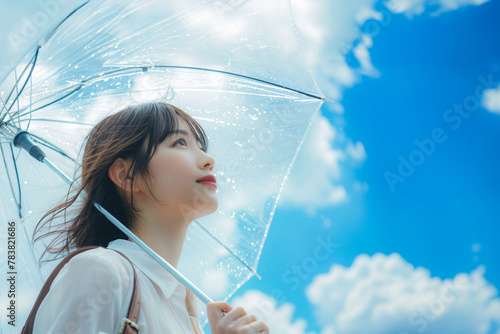 梅雨の晴れ間、雨があがった青空を見上げる通勤中の若いol・会社員・日本人女性(美人モデル)
