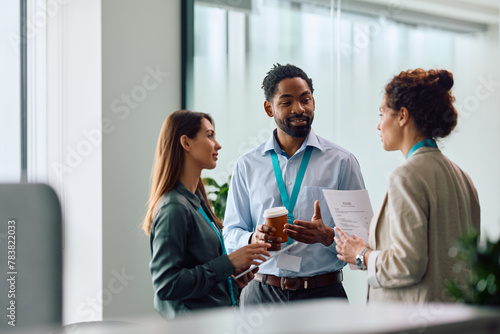 Black businessman talking to female colleagues while working in office.
