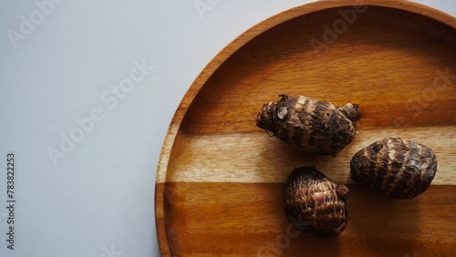 Close up isolated flat lay taro tuber or Colocasia esculenta on a wooden tray. photo