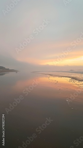 Tranquil beach at dawn with soft pastel skies reflecting on calm waters and gentle tide.