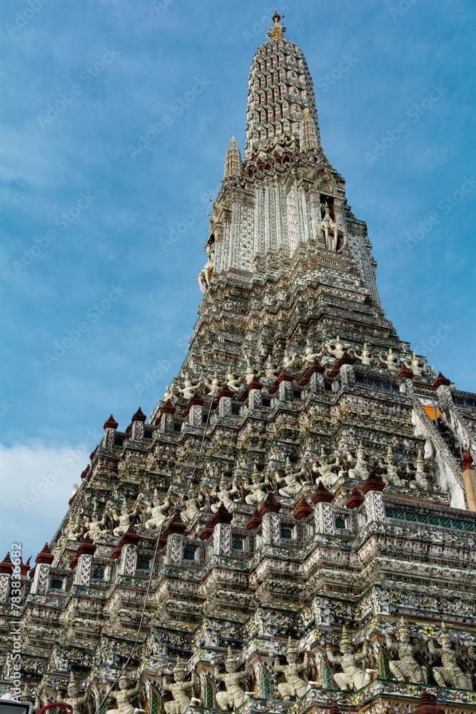 A tall, ornate building with a steeple. The building is covered in intricate designs and has a very grand appearance. The sky above the building is clear and blue, creating a sense of calm