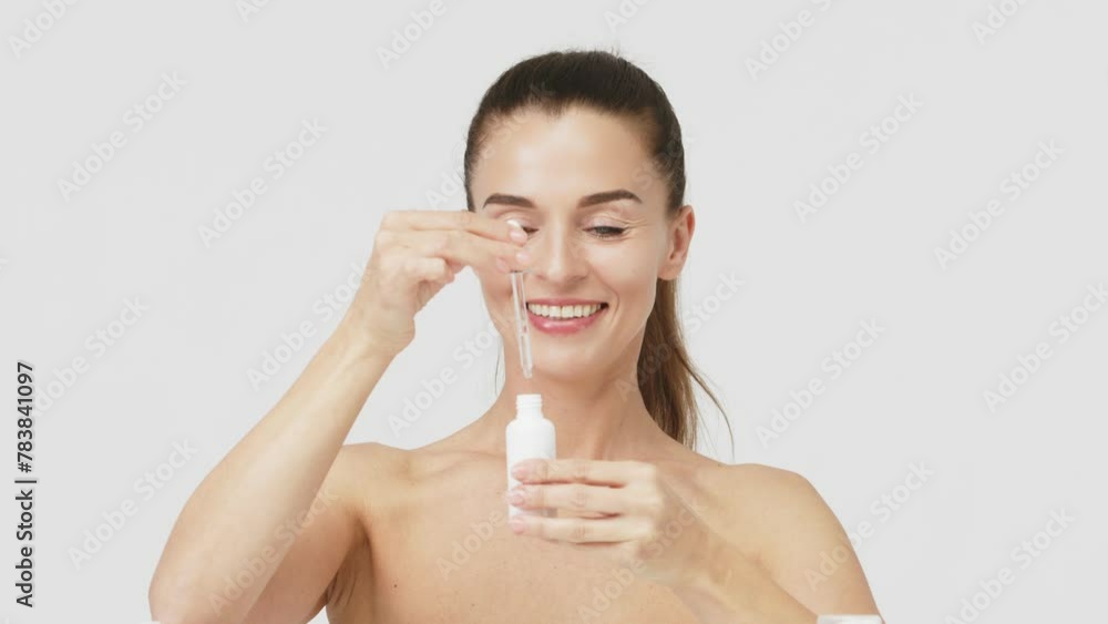 Beautiful middle-aged woman with perfect facial skin after applying moisturizing serum on a white background. Skin care, cosmetics, healthcare and rejuvenation concept. Beautiful middle-aged woman with perfect facial skin after applying moisturizing serum on a white background. Skin care, cosmetics, healthcare and rejuvenation concept.