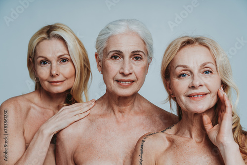 Image of three beautiful senior women posing on a beauty photo session. Middle aged women in lingerie holding hands close to face. Concept about body positivity, self esteem, and body acceptance.