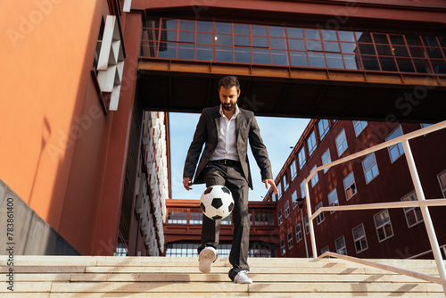 Image of a businessman and soccer freestyle player making tricks with the ball on the street. freestyle soccer player dribbles while walking down the office stairs.