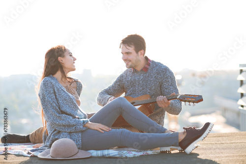 Young man and woman with guitar having fun outdoors