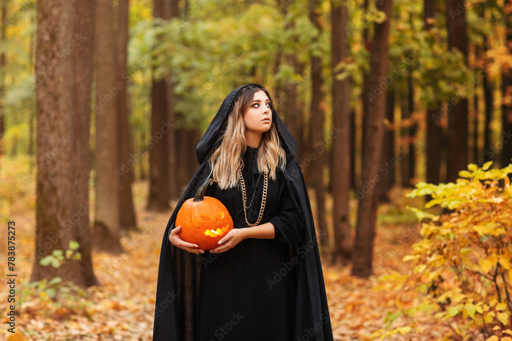 Young witch with jack o lantern in forest Young witch with jack o lantern in forest