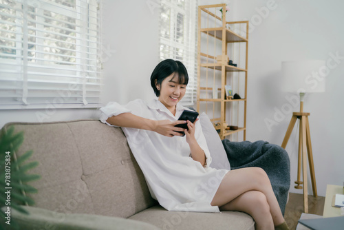 A woman is sitting on a couch and looking at her cell phone