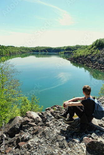 beautiful Summer landscape with blue lake and sitting tourist. rear view. scenic nature view. adventure atmosphere. travel lifestyle. trip, journey, hiking concept.