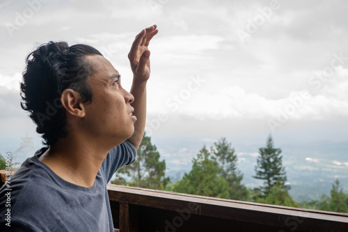 Man sitting near fence and looking the landscape mountain. The photo is suitable to use for calm enjoyed activity, leisure activity and park background.