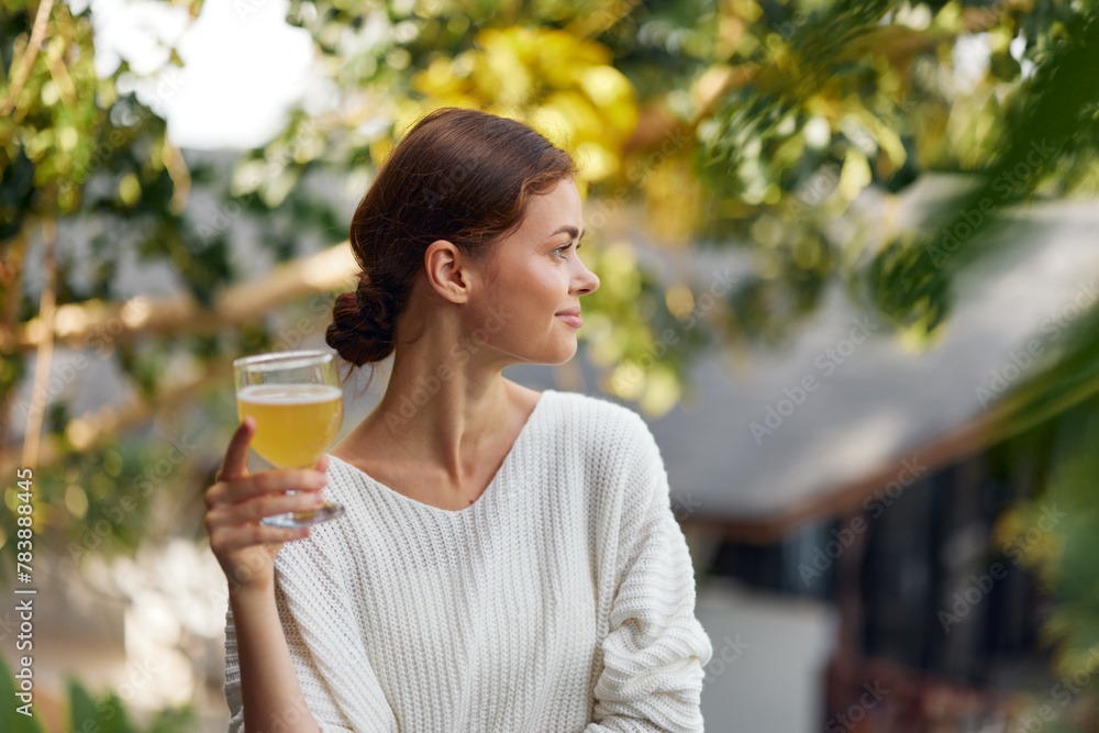 Woman holding a glass of refreshing kombucha outdoors in the sunlight, enjoying a healthy and relaxing moment surrounded by nature The vibrant green scenery adds to the feeling of freshness, while the Woman holding a glass of refreshing kombucha outdoors in the sunlight, enjoying a healthy and relaxing moment surrounded by nature The vibrant green scenery adds to the feeling of freshness, while the